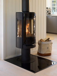 Side view of Aduro 22.3 Lux wood burning stove with glossy glass door and elegant pedestal design.