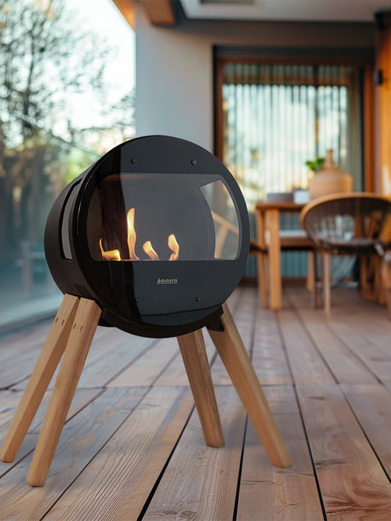 Aduro B1 bioethanol fireplace with glass sides, oak legs, showcasing a 180-degree view of the flame in a modern setting.