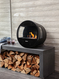 Side view of Aduro B1 bioethanol fireplace with glass door and sides, showcasing elegant Danish design and oak legs.