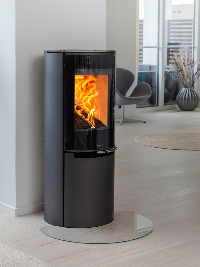 Side view of Aduro H4 Lux Hybrid Stove with glossy glass door and curved front, showcasing sleek design and finish.