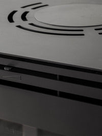 Side view of Aduro H5 Hybrid Stove showcasing its cubic design, smooth surfaces, and elegant handles in a modern interior.
