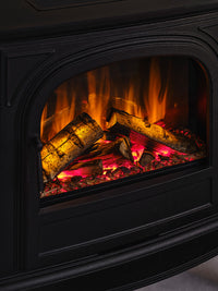 Side view of British Fires Hinton Electric Stove showcasing cast iron body and hand-scorched oak logs with LED lighting.