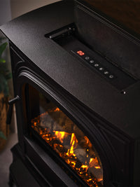 Side view of British Fires Hinton Electric Stove showcasing cast iron body and hand-scorched oak logs with LED mood lighting.