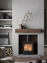 Compact black cast iron Contura 210 wood burning stove with classic door, shown from the front in a cozy setting.
