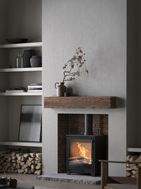 Side view of the Contura 210G wood burning stove with a sleek glass door and modern design, showcasing its compact size.
