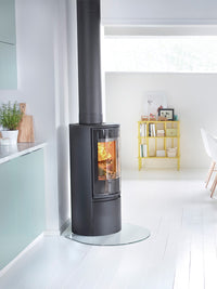 Side view of the Contura 510G wood burning stove with a large glass door, showcasing its sleek black design and curved shape.