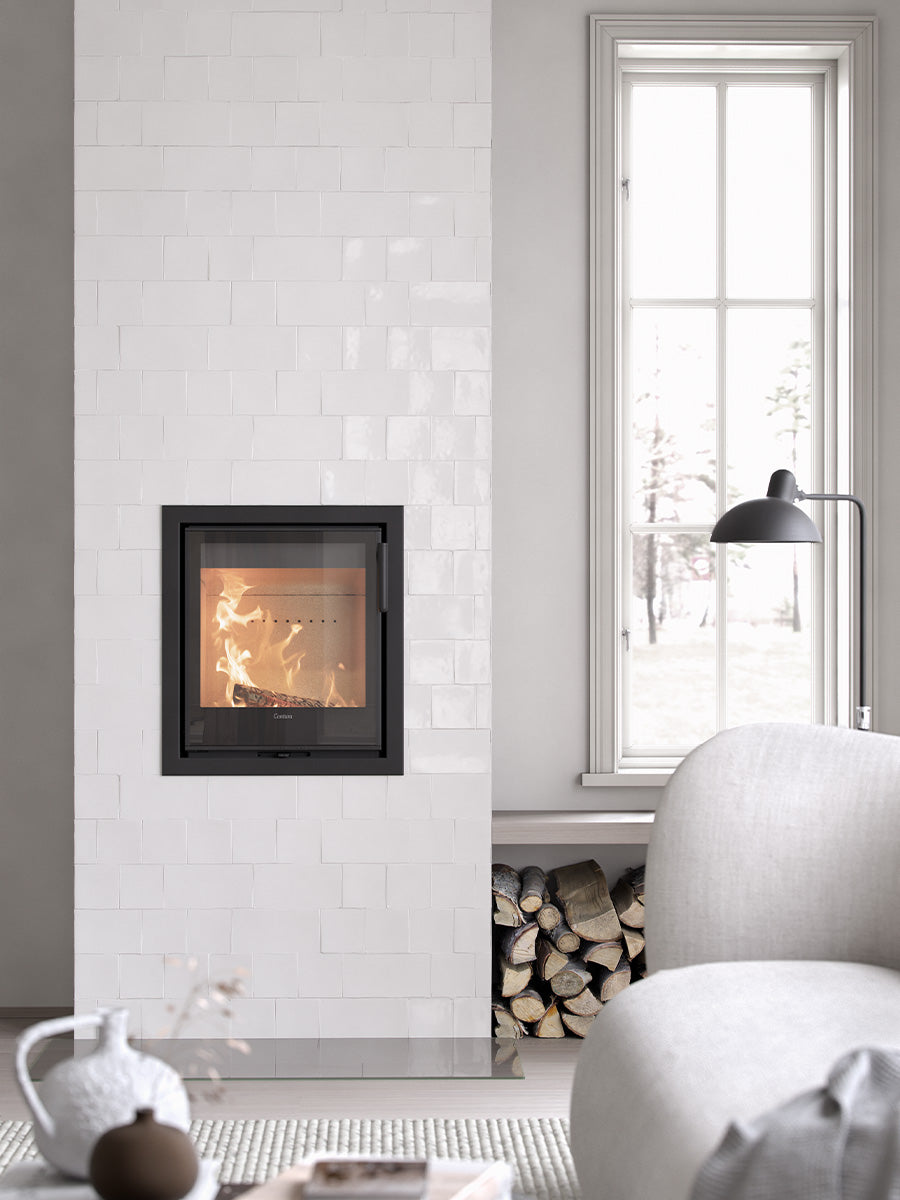 Contura i2G wood burning fireplace insert with glass door, showcasing sleek design and compact format in a cozy setting.