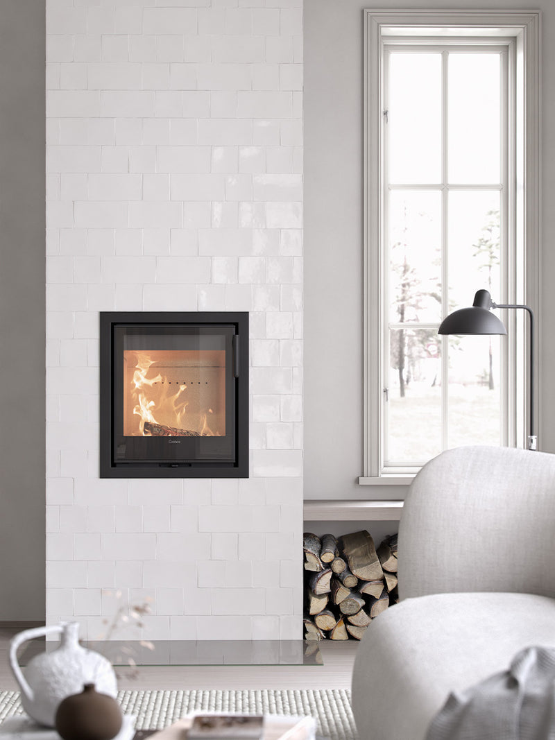 Contura i2G wood burning fireplace insert with glass door, showcasing sleek design and compact format in a cozy setting.