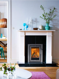 Side view of the Contura i4 wood burning fireplace insert in black, showcasing its sleek glass door and compact design.