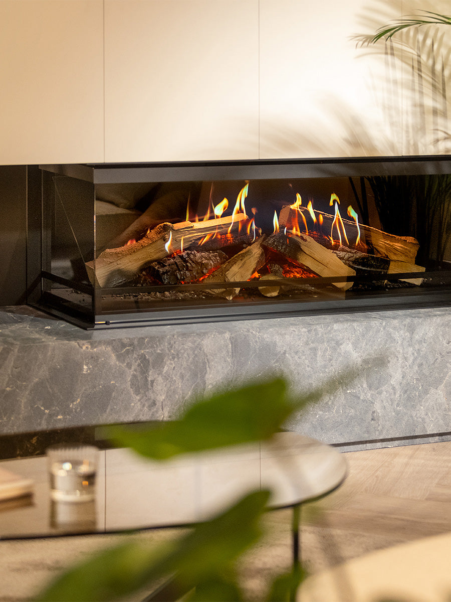 Corner view of Kalfire E-One 130C electric fire with glass front, ceramic logs, and glowing ember bed.