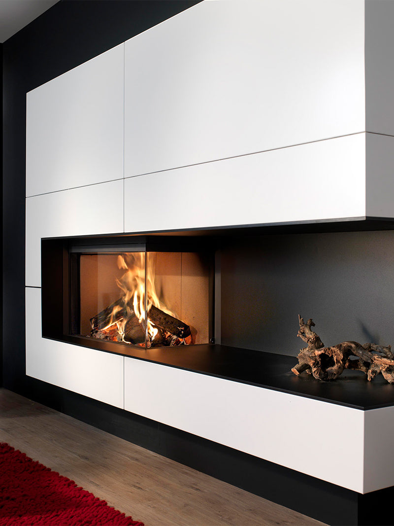 Large corner wood burner with curved ceramic glass, showcasing a sleek design and warm ambiance in a spacious room.