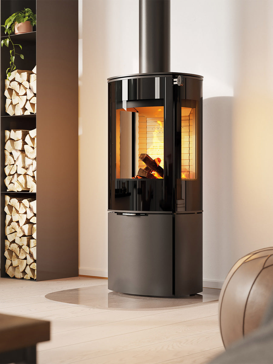 Side view of the RAIS Caro 110 wood burning stove, showcasing its rounded design and large glass door with flames visible.