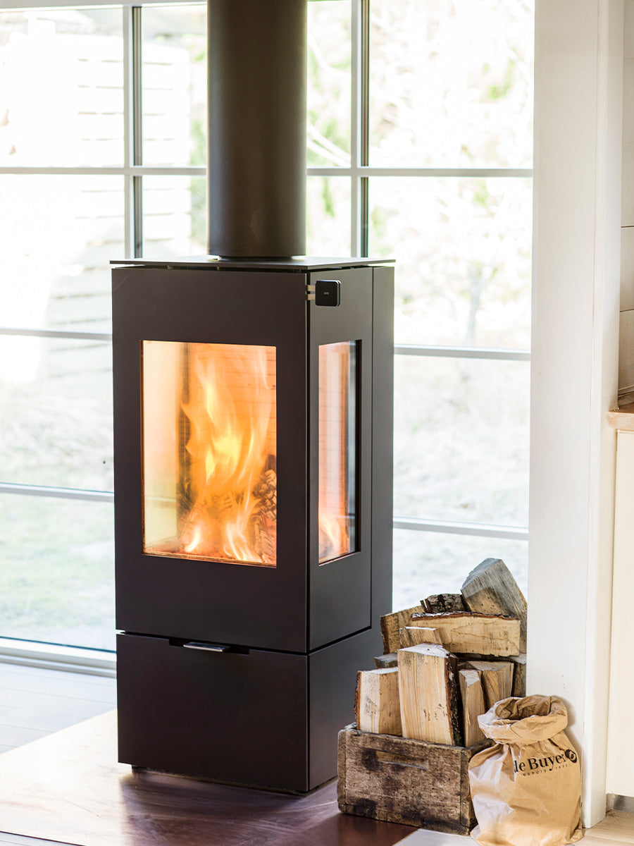 Side view of the RAIS Nexo 100 wood burning stove with a glass door, showcasing its sleek design and large glass panes.