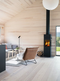 Side view of RAIS Nexo 140 wood burning stove with glass door, showcasing smooth surfaces and large glass panes.