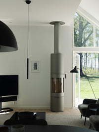 Side view of the RAIS PILAR wood-burning stove showcasing its tall, sculptural design and panoramic glass.