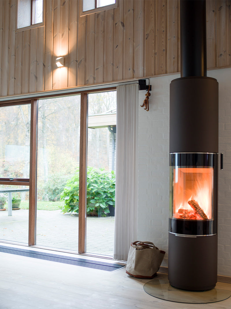 Side view of the RAIS PILAR wood-burning stove showcasing its sleek design and panoramic glass for flame visibility.