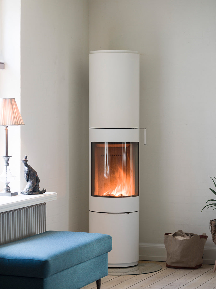Sculptural RAIS PILAR wood-burning stove with curved glass, showcasing flames from a front view on a sleek base.