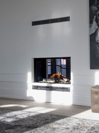 Side view of RAIS Visio 100 T gas fireplace insert tunnel with black frame, showcasing flames visible from both rooms.
