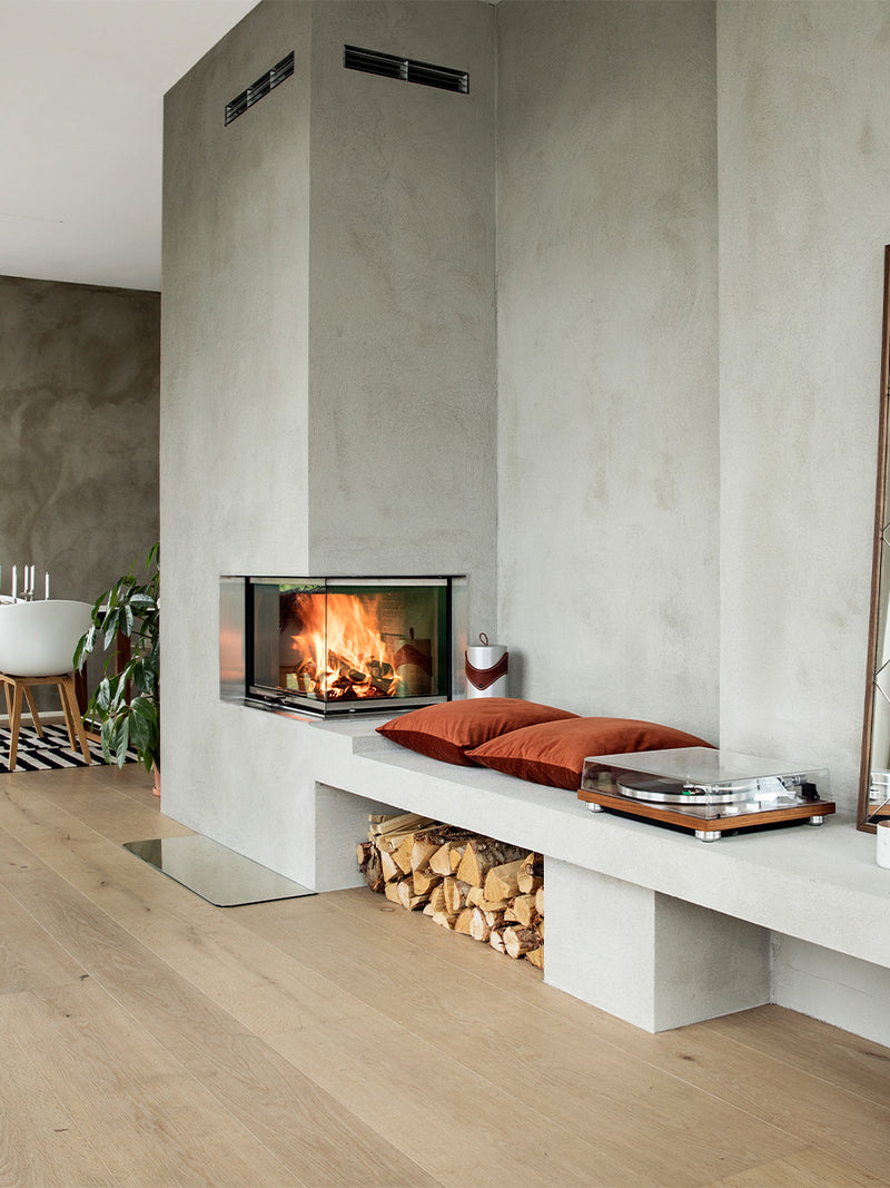 Side view of RAIS Visio 2 wood burning stove with glass on two sides, showcasing its corner installation design.