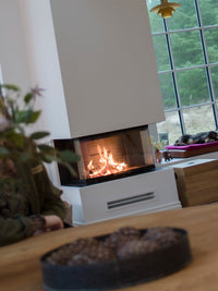 Side view of the RAIS Visio 3 wood burning stove with three glass sides, showcasing its elegant design and wood finish.