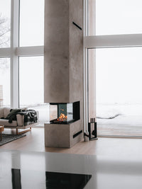 Side view of RAIS Visio 3:1 wood burning stove room divider, showcasing glass panels and sleek design in a modern setting.