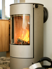 Side view of the RAIS Viva L 100 wood burning stove with a curved glass door and sleek black finish.