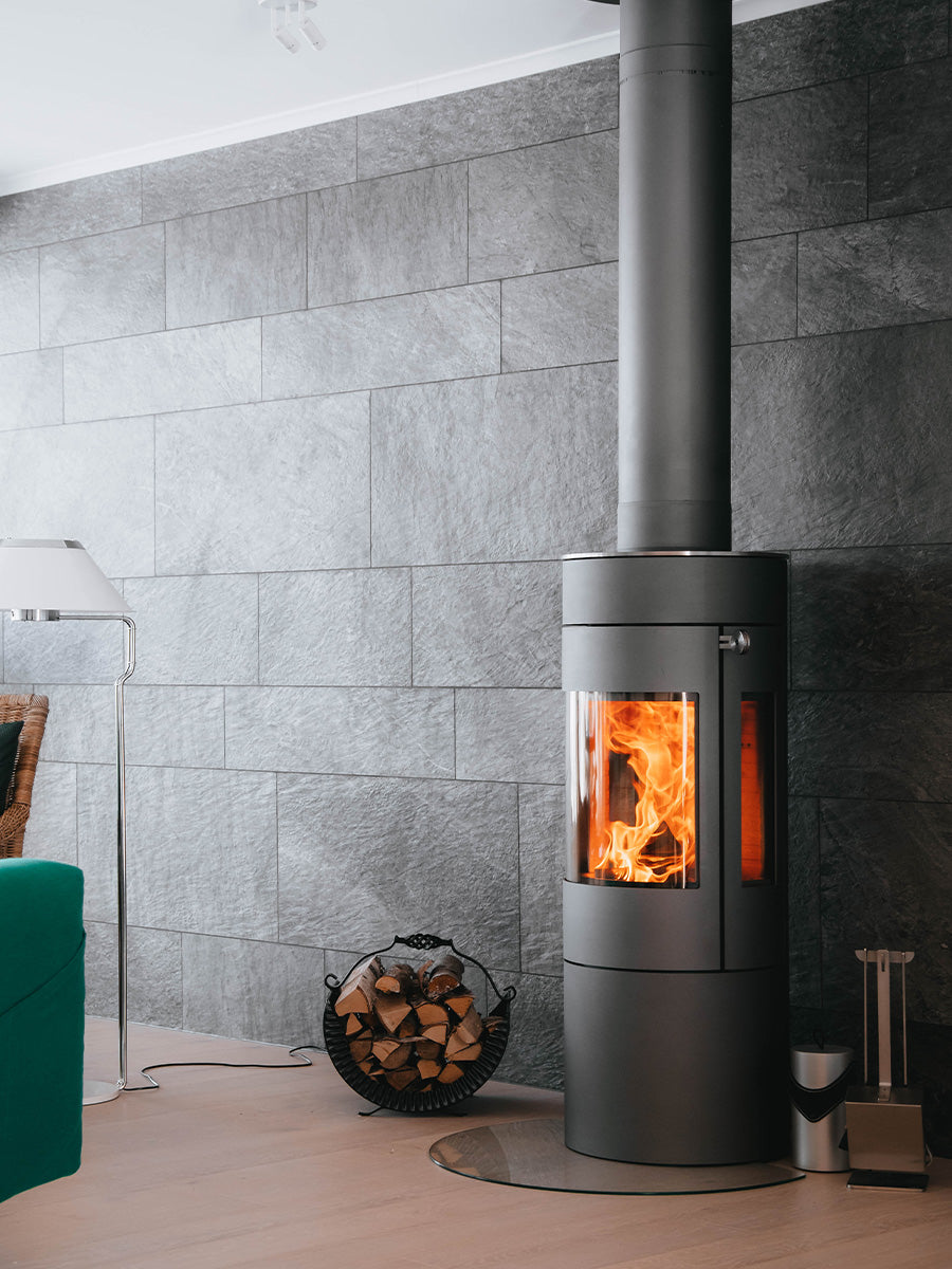 Side view of RAIS Viva L 120 wood burning stove with a curved glass door and sleek black finish.