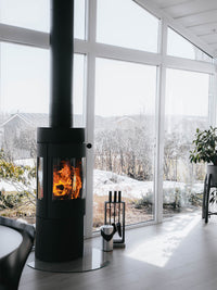 Side view of the RAIS Viva L 120 wood burning stove with a glass door, showcasing its sleek design and curved glass.
