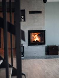 Side view of Rais 600 2 Inset Wood Burning Stove in black, showcasing large glass panes and corner design.