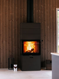 Side view of RAIS 600 Max wood burning stove with steel door and three storage boxes, showcasing elegant design and finish.